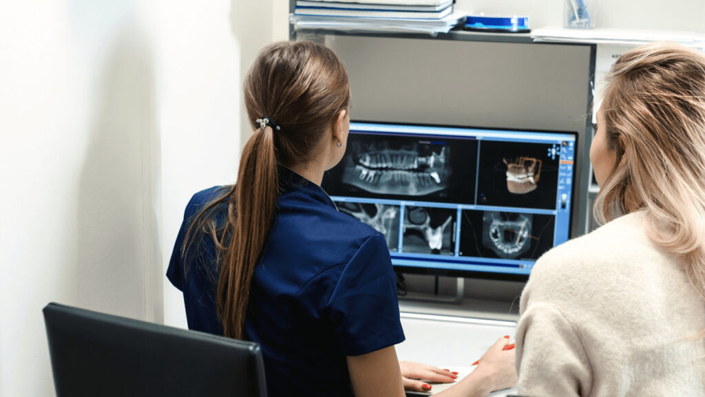 Two women examining a full arch restoration x-ray.